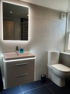 a bathroom with a toilet and a sink and a mirror at Laburnam Villa - Luxury 4 bedroom accommodation in the heart of Killin in Killin