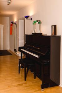 a black piano sitting in a living room at Modernes und gemütliches Designerzimmer in Langensteinbach