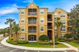 een geel appartementengebouw met palmbomen en een straat bij Windsor Hills Resort 3 Bedroom Condo 5 Minutes to Disney in Orlando