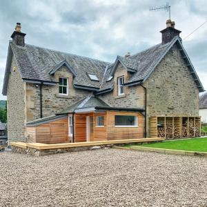 a large stone house with a wooden facade at Laburnam Villa - Luxury 4 bedroom accommodation in the heart of Killin in Killin