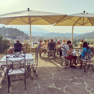 um grupo de pessoas sentadas em mesas sob um guarda-chuva em Hotel Vila Aleksander em Berat