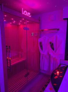 Cette chambre est dotée de lumières roses et d'une douche avec des vêtements. dans l'établissement L'Aurore suite de charme, clim jacuzzi, sauna, piscine chauffée cuisine..., à Carpentras