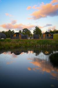 a couple of houses in a field next to a pond at Newmore Highland Pods with Hot Tubs on NC500 in Invergordon