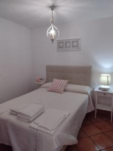 1 dormitorio con cama con sábanas blancas y luz en La Casita de Zahara de la Sierra, en Zahara de la Sierra