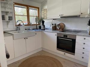 een keuken met witte kasten, een wastafel en een fornuis bij Holiday home VäTö IV in Harg