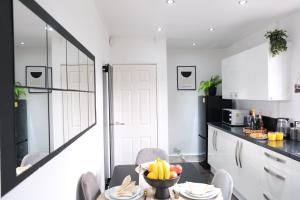 a kitchen with white cabinets and a table with a bowl of fruit at Bee Stays - Northway House in Warrington