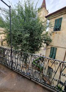 a black fence in front of a building with a tree at Alla Mezzora - Finalborgo in Finale Ligure