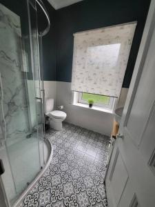 a bathroom with a shower and a toilet and a window at Castleside House in Matlock