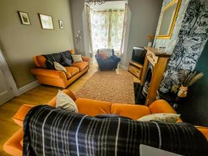 a living room with an orange couch and a fireplace at Castleside House in Matlock