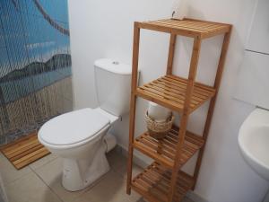 a bathroom with a toilet and a wooden shelf at Les jardins d'Émilie in Le Moule