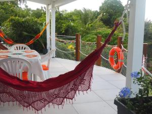 a hammock on a porch with a table and chairs at Les jardins d'Émilie in Le Moule
