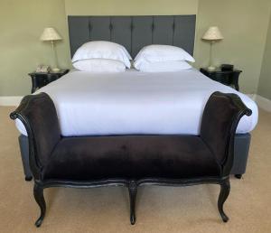 a large bed with a black leather headboard and white pillows at Fernhill Hotel in Lyme Regis