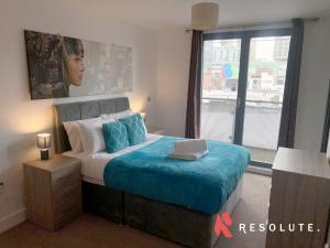 1 dormitorio con cama con sábanas azules y ventana en Stylish Arcadian Centre - One Bedroom - Large Balcony - Bullring Shopping en Birmingham