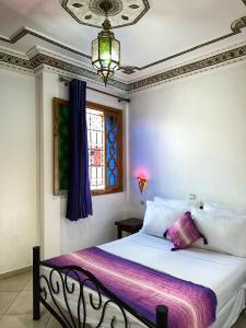a bedroom with a bed with white sheets and a window at Dar Rehab in Rabat