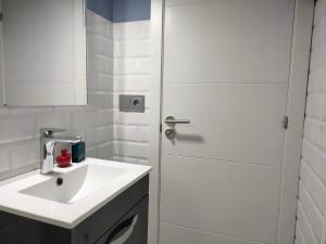 La salle de bains blanche est pourvue d'un lavabo et d'une porte de douche. dans l'établissement Claro de Luna, à Pontevedra