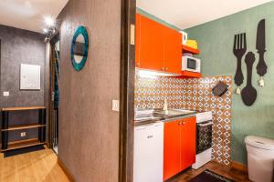 une petite cuisine avec des armoires orange et un évier dans l'établissement Pied des pistes - Balcon - Chiens bienvenus, à Saint-Jean-dʼAulps 9 autres photos