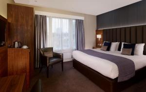 um quarto de hotel com uma cama e uma cadeira em Norfolk Towers Paddington em Londres