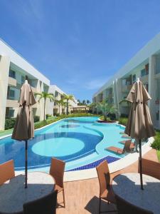 una piscina con due tavoli e ombrelloni di Flat Guarajuba, Charmoso Porto Smeralda a Guarajuba