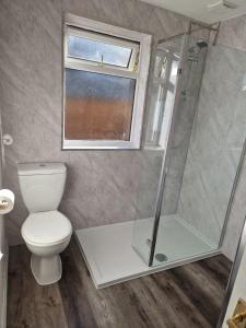 ein Bad mit einer Dusche, einem WC und einem Fenster in der Unterkunft Fab-u-Luss in Luss