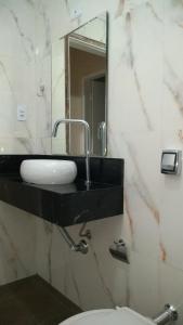 La salle de bains est pourvue d'un lavabo, d'un miroir et de toilettes. dans l'établissement Recanto Bessa Praia Grande aceito cartão, à Praia Grande