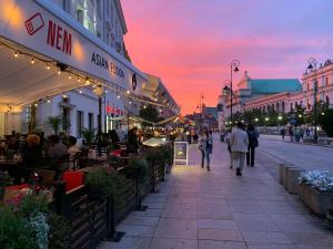 a group of people walking down a street at sunset at Jess Hotel & Spa Warsaw Old Town in Warsaw
