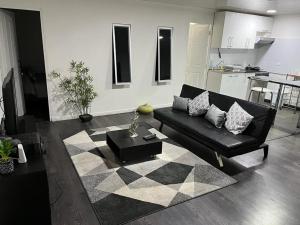 ein Wohnzimmer mit einem schwarzen Sofa und einem Tisch in der Unterkunft Departamento en segundo piso de casa familiar in Iquique