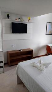 a bedroom with a bed and a flat screen tv at Victória Marina Flat in Salvador