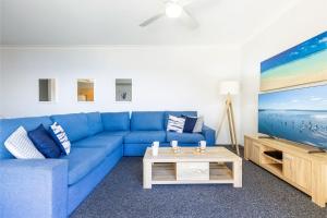 sala de estar con sofá azul y TV en Kiah, 12,53 Victoria Pde - Panoramic water views, Wifi and Air Con en Nelson Bay