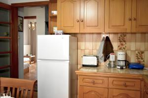 a kitchen with a white refrigerator and wooden cabinets at Κεντρικό και ευρύχωρο οροφοδιαμέρισμα in Kastoria