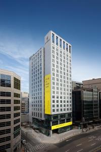 a tall white building with a yellow sign on it at L7 Myeongdong by LOTTE in Seoul