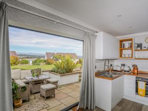 a kitchen and living room with a view of a patio at Trem Y Borth Apartment in Abersoch