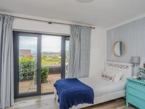 a bedroom with a bed and a large window at Trem Y Borth Apartment in Abersoch