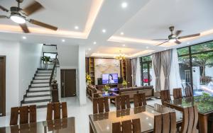 a living room with a table and chairs and a staircase at Sea Breeze Villa FLC sang trọng gần biển có bể bơi in Sầm Sơn