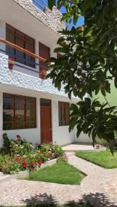 uma casa branca com flores à frente em Las Palmeras Eco Hostel em Cabanaconde
