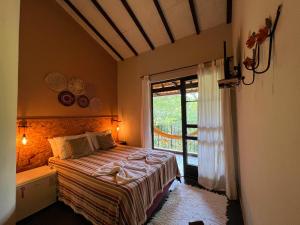 a bedroom with a bed and a large window at Sarandy Hotel Eco Parque in Paraíba do Sul