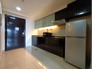 eine Küche mit schwarzen Schränken und einem Kühlschrank aus Edelstahl in der Unterkunft Resort Suites by Landmark at Bandar Sunway Sunway Lagoon in Kampong Penaga