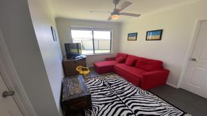 a living room with a red couch and a zebra rug at Adriana Retreat, 20 Adriana Retreat in Jurien Bay