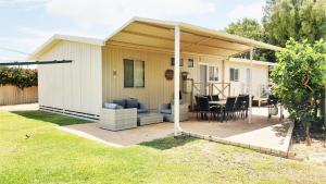 una casa con un patio con mesa y sillas en Frangipani Cottage, en Jurien Bay