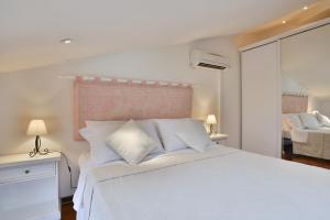 een witte slaapkamer met een groot bed met witte kussens bij Holiday Alghero in Alghero