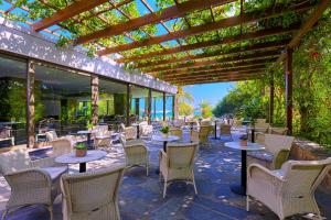 a patio with tables and chairs and a pergola at Sitia Beach City Resort & Spa in Sitia