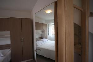 een kleine slaapkamer met een bed en een spiegel bij Apartments Sonja in Pučišća