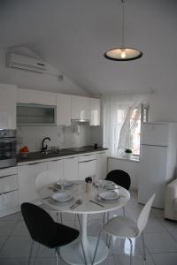 een witte keuken met een witte tafel en stoelen bij Apartments Sonja in Pučišća
