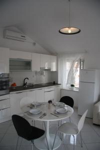 a white kitchen with a white table and chairs at Apartments Sonja in Pučišća