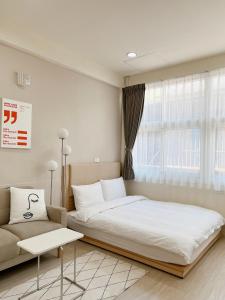 a bedroom with a large bed and a couch at HoHo Woo Tainan Homestay in Tainan