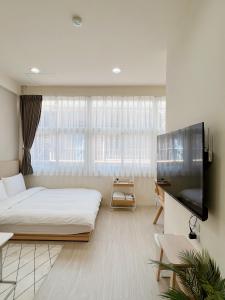 a bedroom with a large bed and a flat screen tv at HoHo Woo Tainan Homestay in Tainan