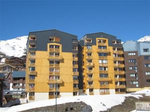 un immeuble d'appartements jaune avec de la neige devant lui dans l'établissement Appartement Val Thorens, 2 pièces, 4 personnes - FR-1-637-45, à Val Thorens