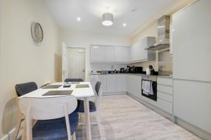- une cuisine avec des placards blancs, une table et des chaises dans l'établissement The Norfolk - comfortable 1 Bedroom Apts with Parking, Maidenhead by 360Stays, à Maidenhead