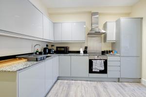 - une cuisine blanche avec des placards blancs et un évier dans l'établissement The Norfolk - comfortable 1 Bedroom Apts with Parking, Maidenhead by 360Stays, à Maidenhead