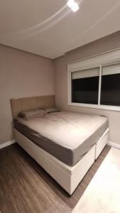 a bed in a bedroom with a window at Apartamento completo na praia brava in Itajaí