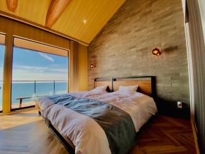 a bedroom with a large bed with a view of the ocean at AWAJI OCEAN BASE in Tusi
